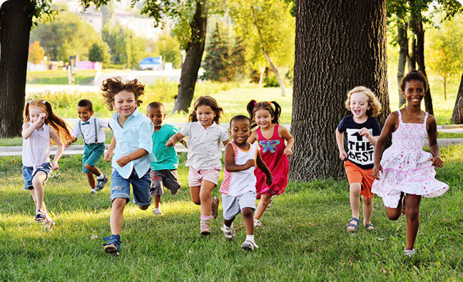 Eight diverse kids in a park run towards camera smiling