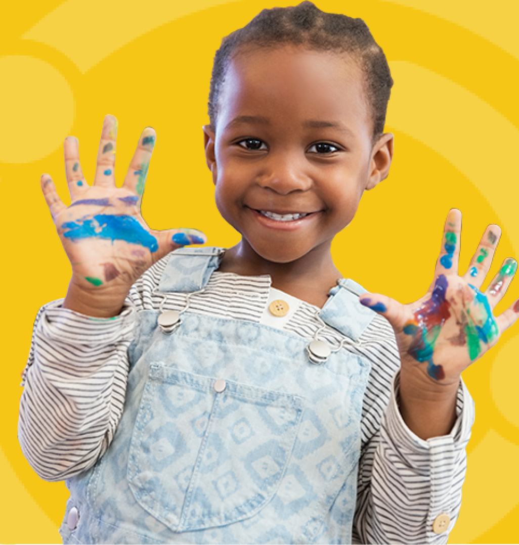 Young black girl with braids smiles at the camera, showing her two paint covered hands